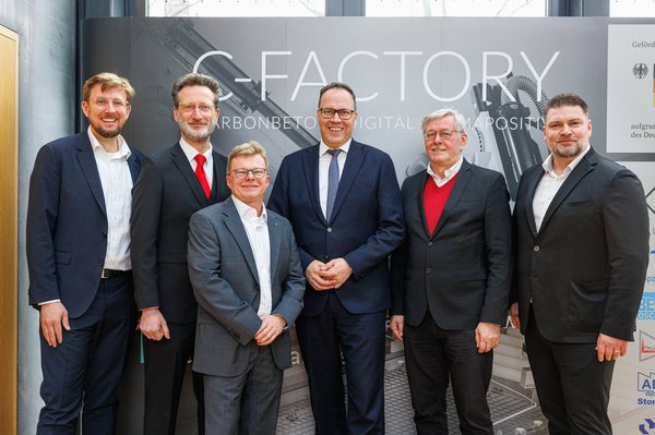 Sechs Männer vor breitem RollUp mit Aufschrift C-Factory