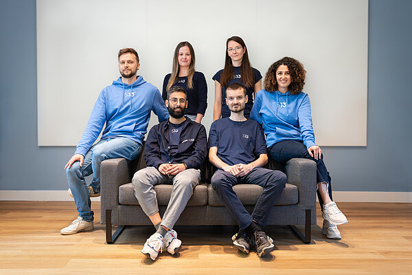 Teamfoto Startbahn 13 6 Personen sitzen auf einer Couch