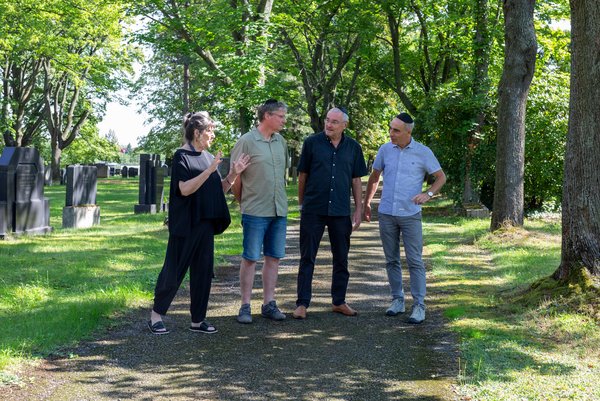 Neuer Israelitischer Friedhof Vier Personen auf einem parkähnlichen jüdischen Friedhof