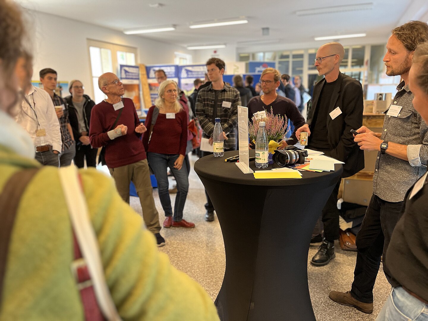 Menschen rund um Stehtisch, reden miteinander