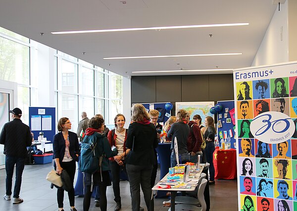 Studierende und Mitarbeiter stehen an einem Infostand
