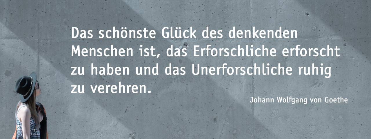 Header-Bild; Frau schaut auf Betonfassade mit Zitat von Johann Wolfgang von Goethe. Zitatbeginn: Das schönste Glück des denkenden Menschen ist, das Erforschliche erforscht zu haben und das Unerforschliche ruhig zu verehren. Zitatende